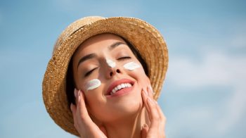 femeie care aplica un produs cu protectie solara